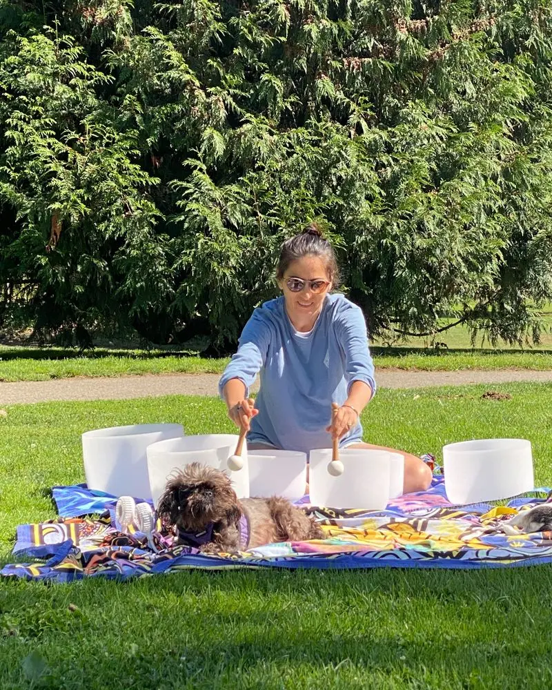 Day playing crystal singing bowls outdoors with her dogs nearby