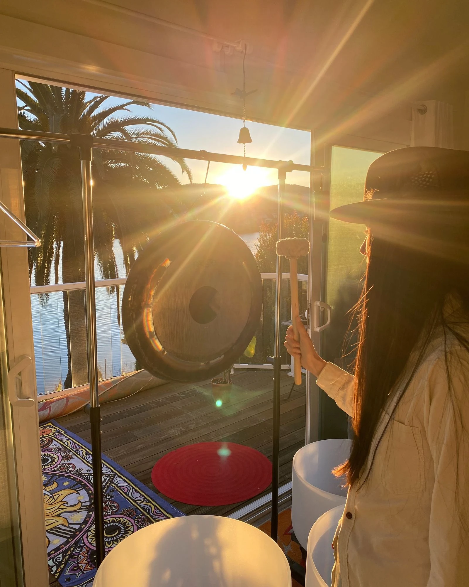 Day playing a gong as sunlight fills the sound bath space