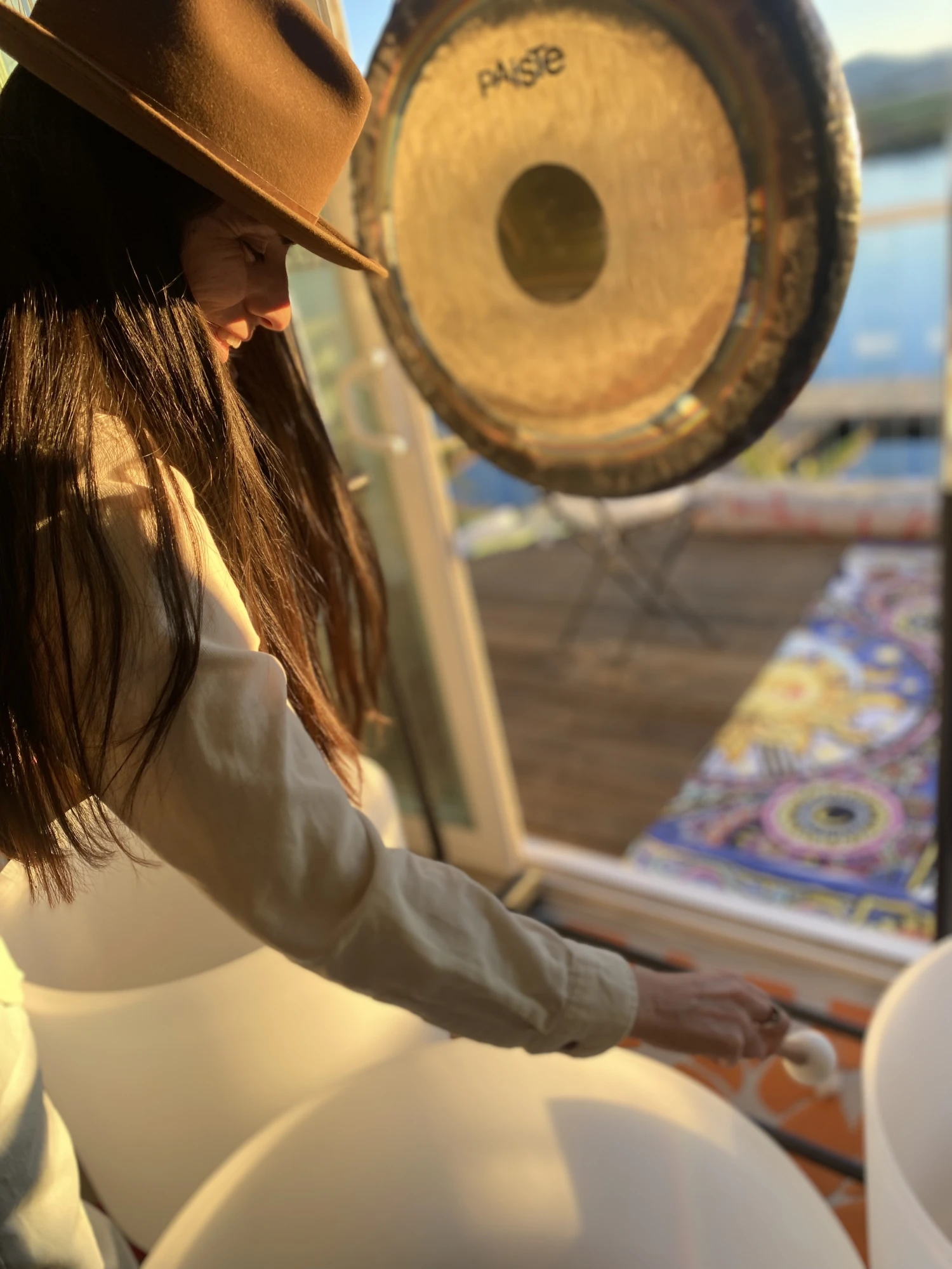 Day playing a crystal singing bowl with a gong nearby